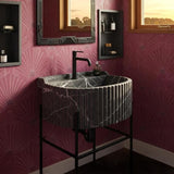 A fluted black marble sink set on a matte black base, styled against a bold pink wallpaper for a dramatic luxury bathroom look.