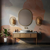 A gray marble bathroom vanity with rattan-front drawers and a vessel sink, framed by elegant brass fixtures.